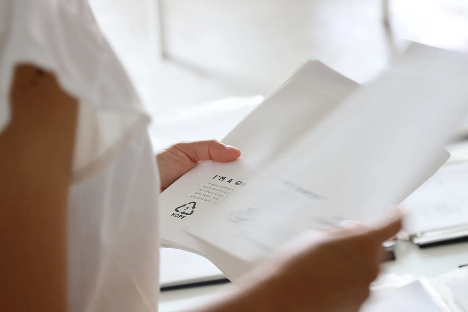 Person holding a white product packaging with text and symbols.