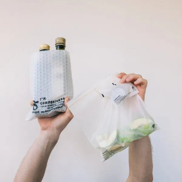 Hands holding up compostable bubble pockets and compostable ziplock bags